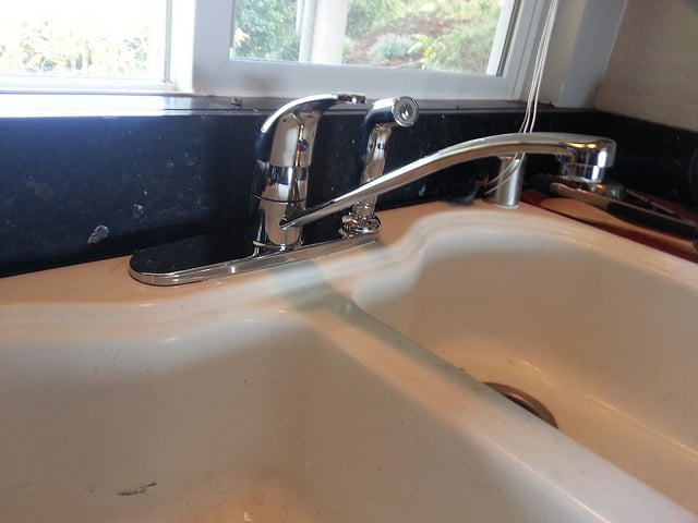 A shiny chrome kitchen faucet over a white sink, illustrating quality plumbing work by Duncan Plumbing Ent., Inc. in Santa Cruz.